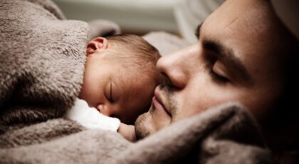 close up of a dad and his little baby sleeping together