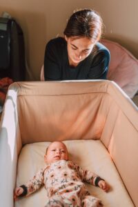 a mother looking on her baby lying on the crib