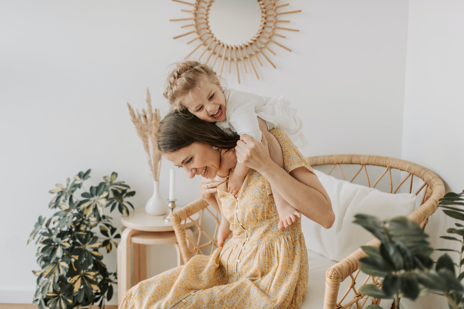 woman in yellow floral dress with baby girl hugging her