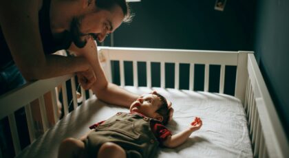 caring father stroking baby in bed