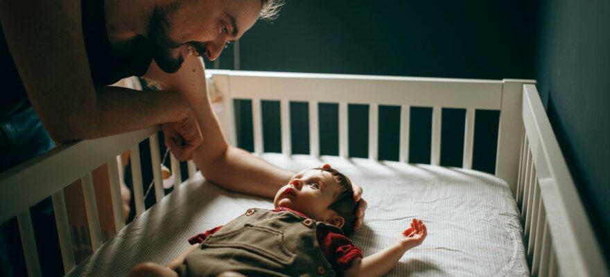 caring father stroking baby in bed