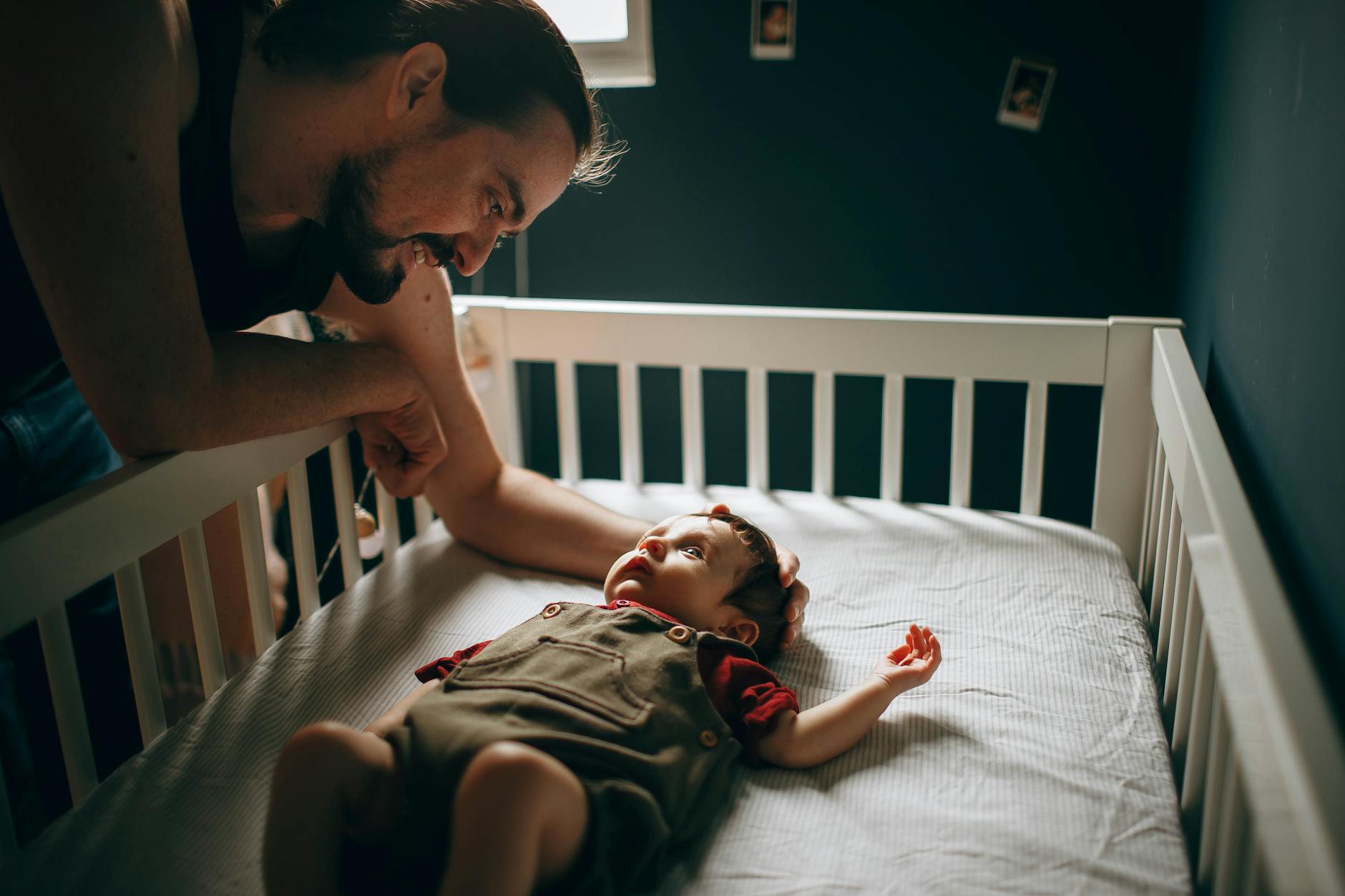 caring father stroking baby in bed