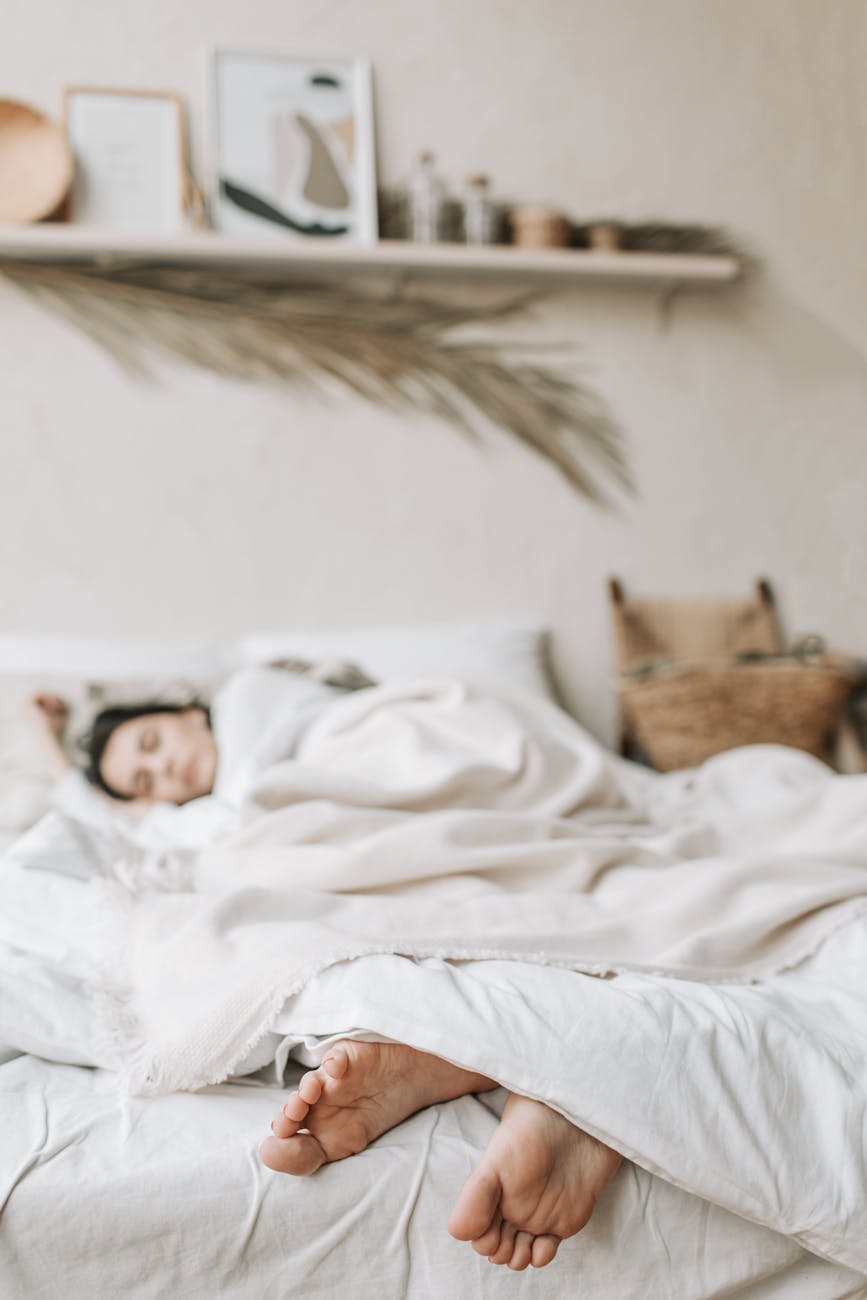 photo of a woman sleeping on a bed with a white blanket
